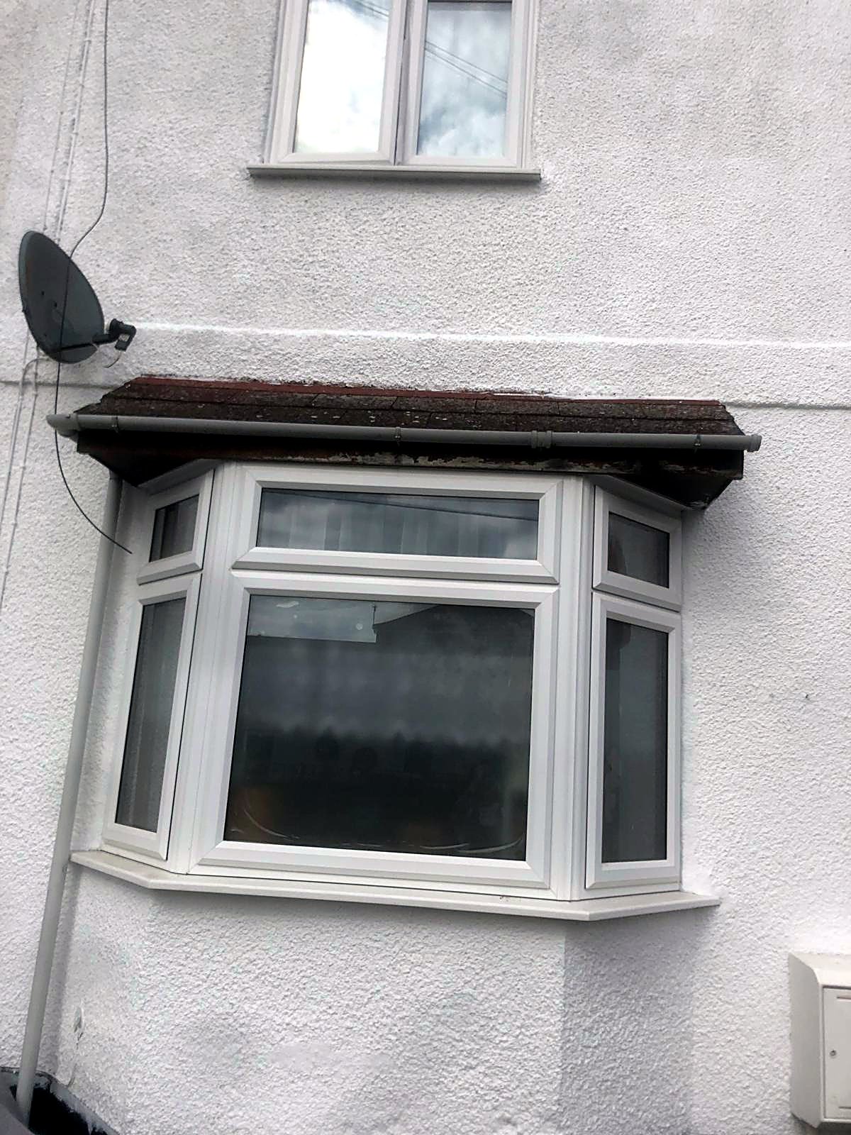 White uPVC bay window under a tiled canopy